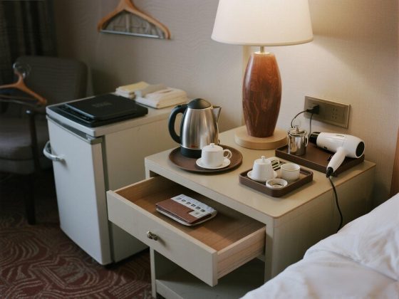 jimeng-2025-07-14-4256-图片描述： 酒店书桌或茶水柜上摆放着：电热水壶、茶杯托盘、吹风机、衣架、小冰箱、...